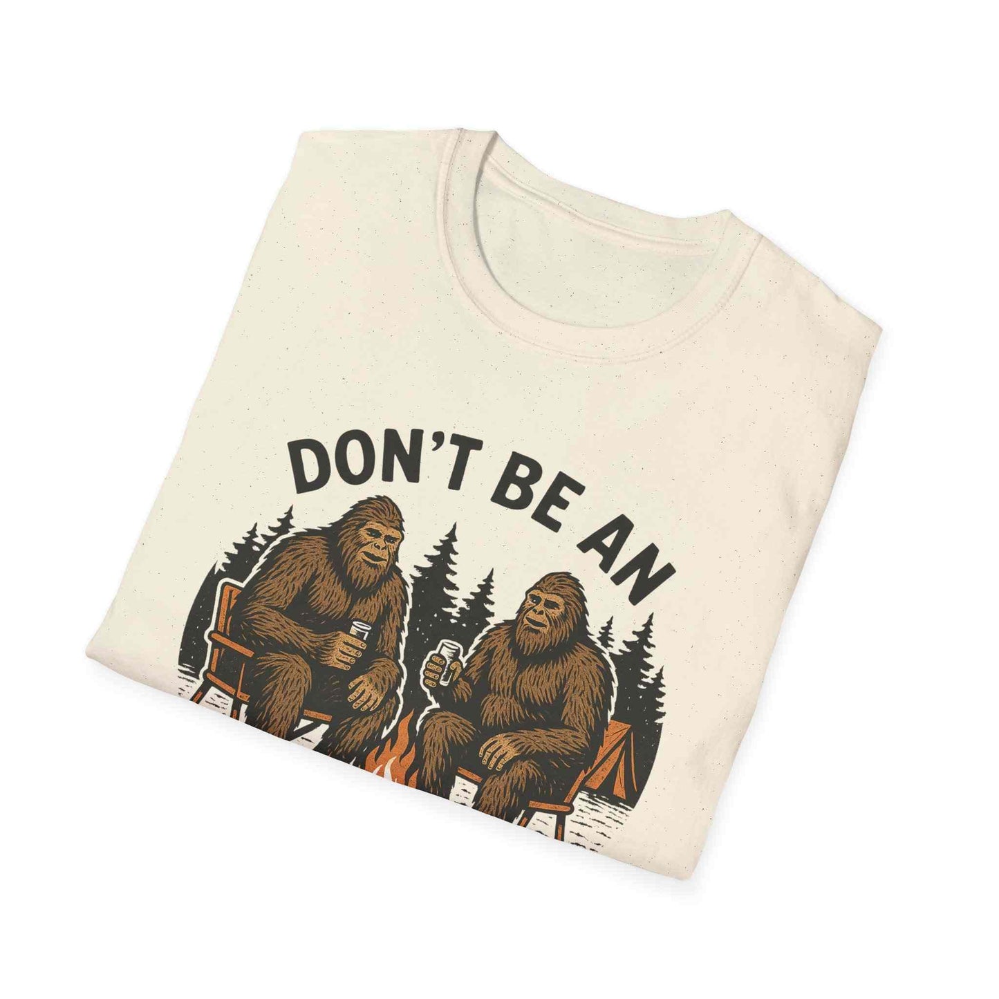 Funny Sasquatch Camping T-Shirt with playful Bigfoot design and outdoor theme on folded cream tee