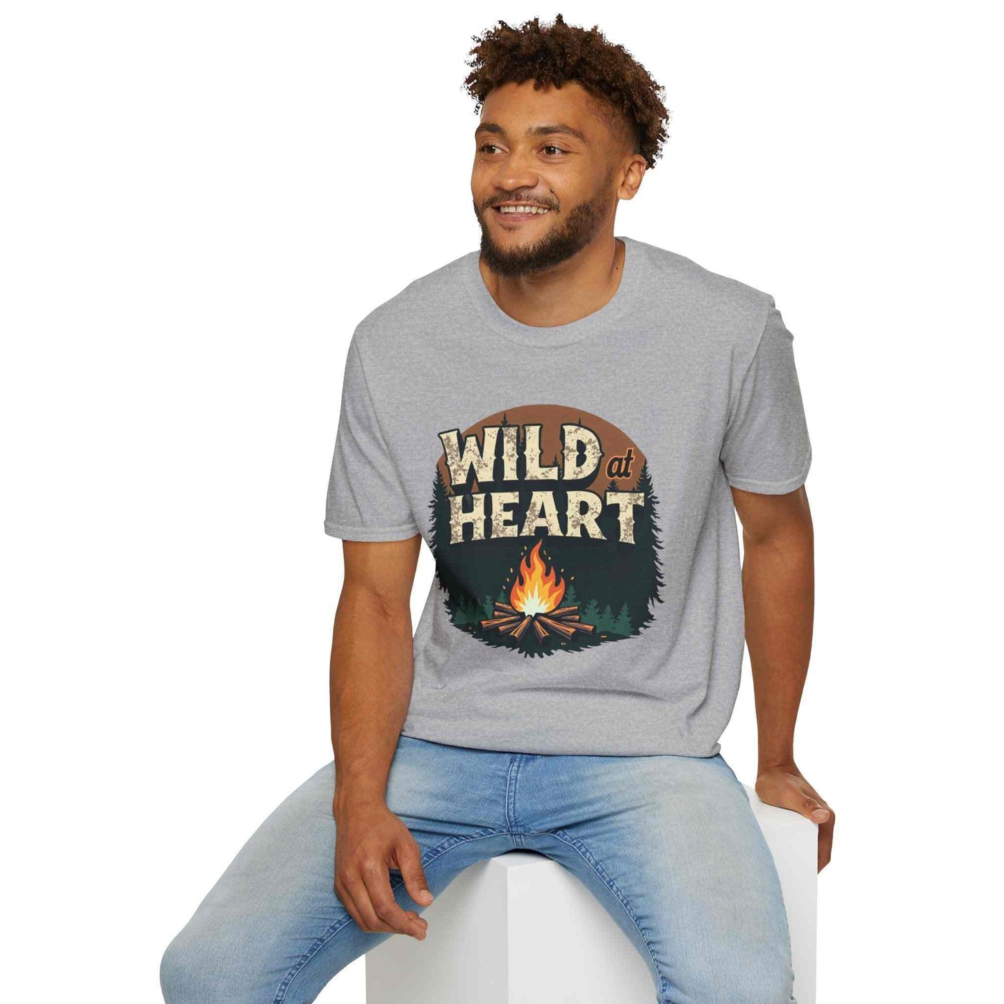 Man wearing grey Wild at Heart Camping T-Shirt with campfire graphic and jeans sitting and smiling